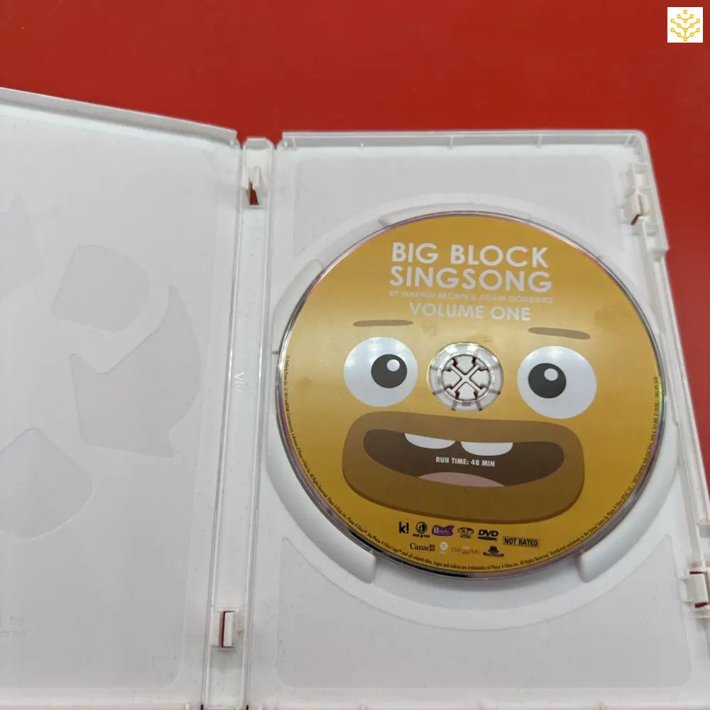 DVD disc with a yellow cartoon face design labeled ’Big Block Singsong Volume One’ inside a white case.