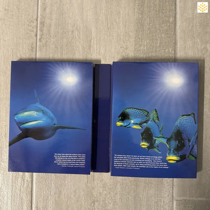 Two open books showing underwater photographs of a shark and tropical fish.