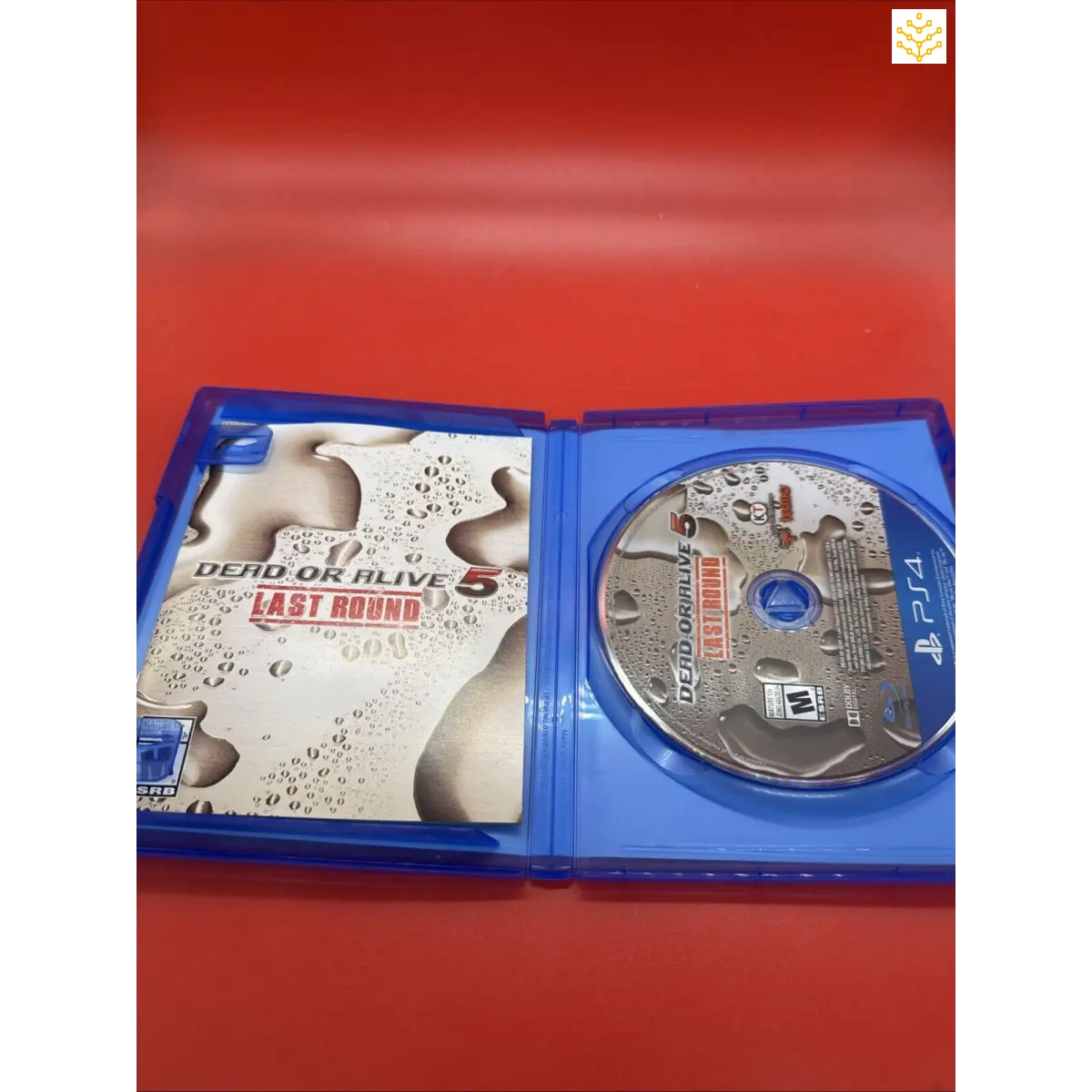 PlayStation 4 game case for ’Dead or Alive: Last Round’ opened to show the disc inside.