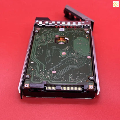 Hard drive with its circuit board exposed, mounted in a server tray.