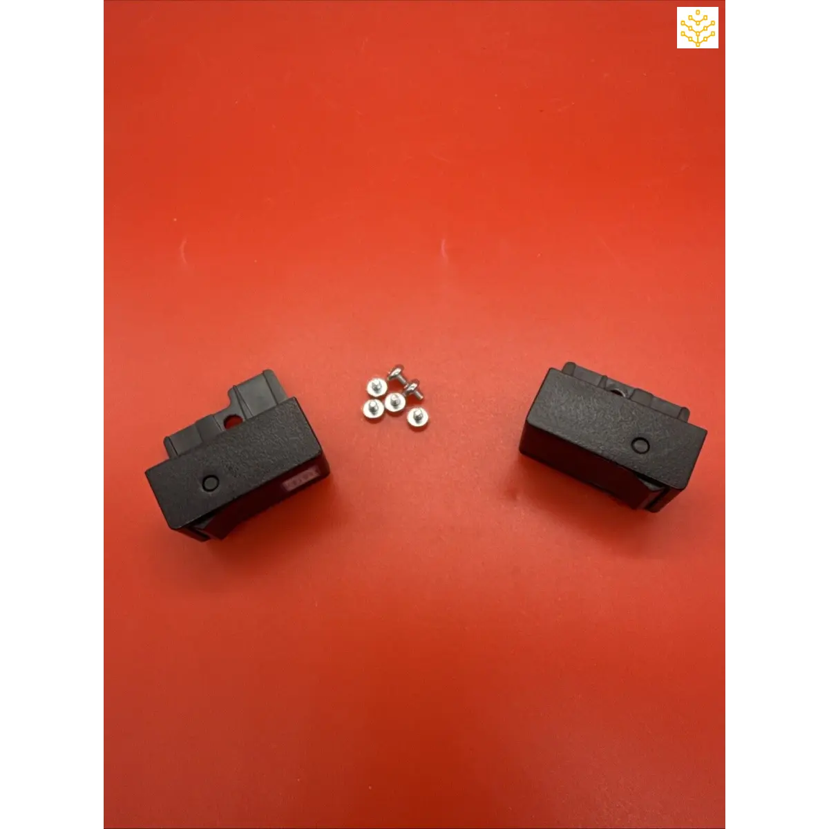 Two black electronic or mechanical components with small metal nuts between them.