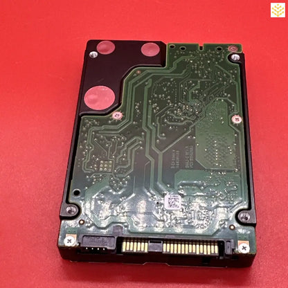 Hard drive or solid-state drive with its circuit board exposed.