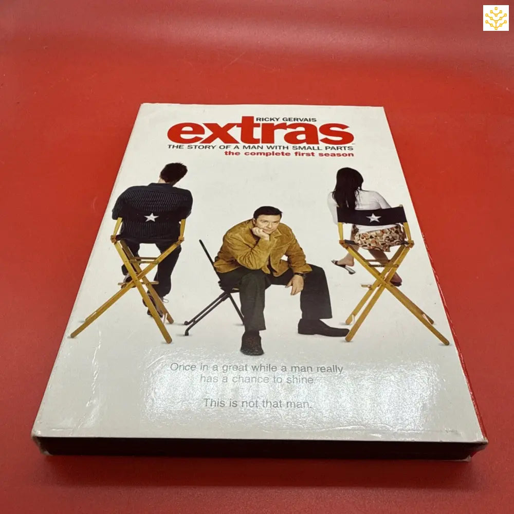 DVD case or movie cover for ’Extras’ featuring three people sitting on director’s chairs against a white background.