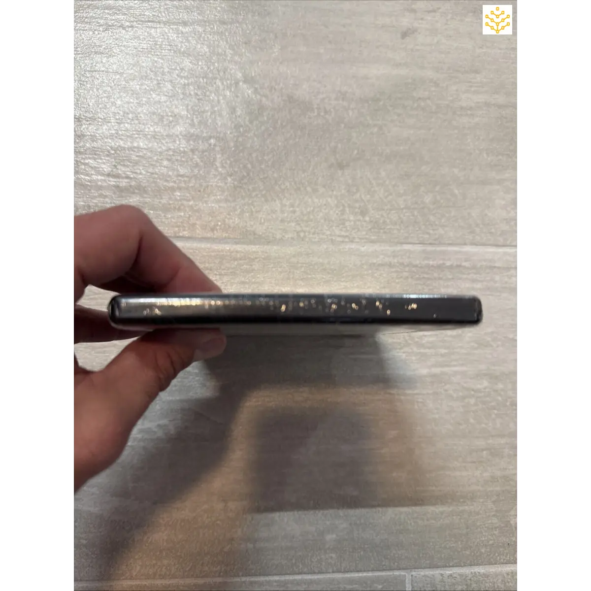 Metallic pen or stylus with small dots or perforations along its length.