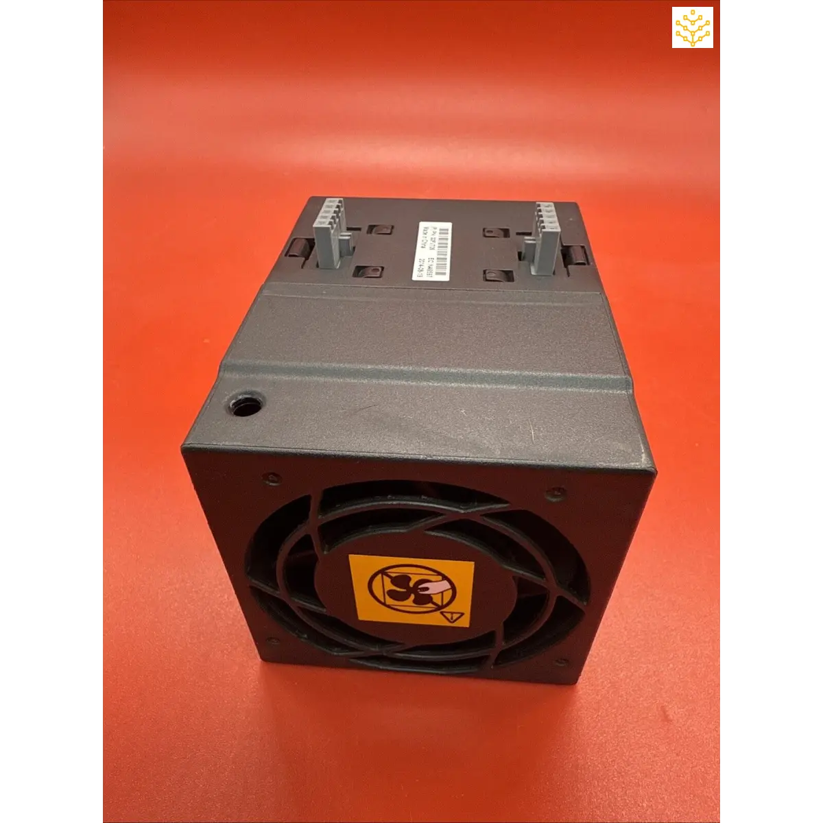 Black computer cooling fan module with circular vents and a yellow warning label.