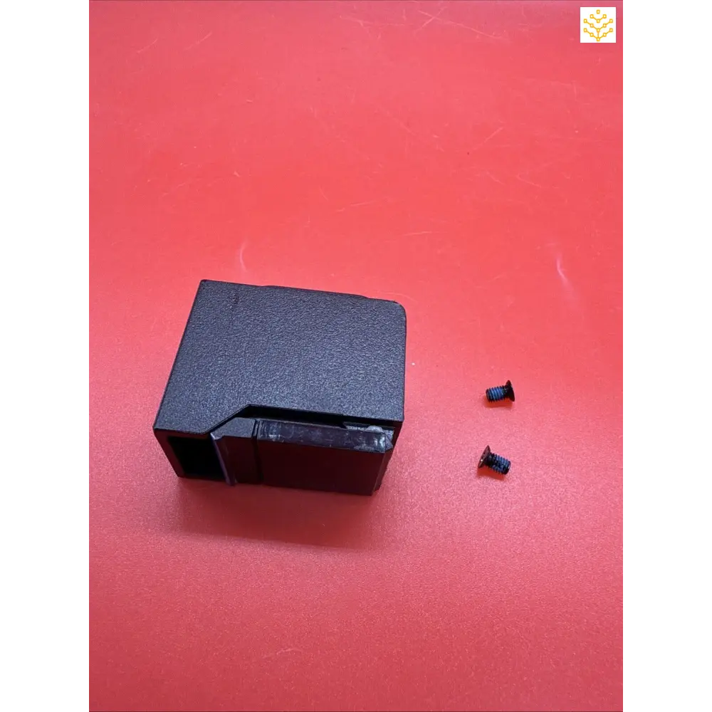 Black plastic electronic device or component with two small detached pieces nearby.