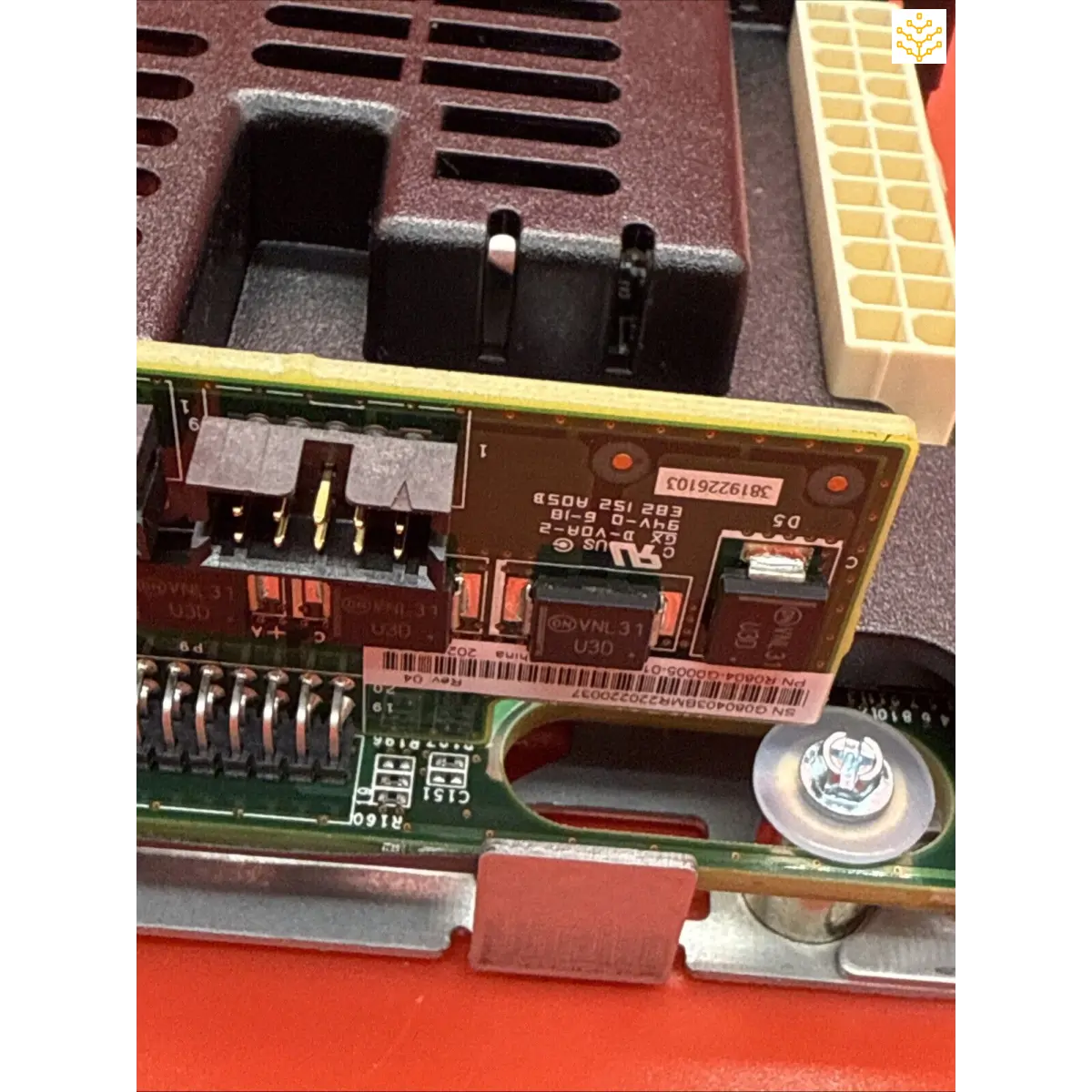 Circuit board with electronic components and connectors mounted on a red surface.