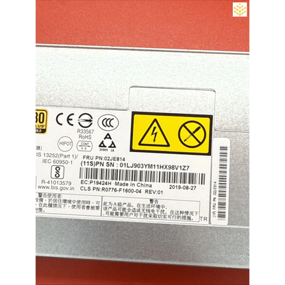 Electronic device component with warning labels and technical specifications printed on its metal casing.