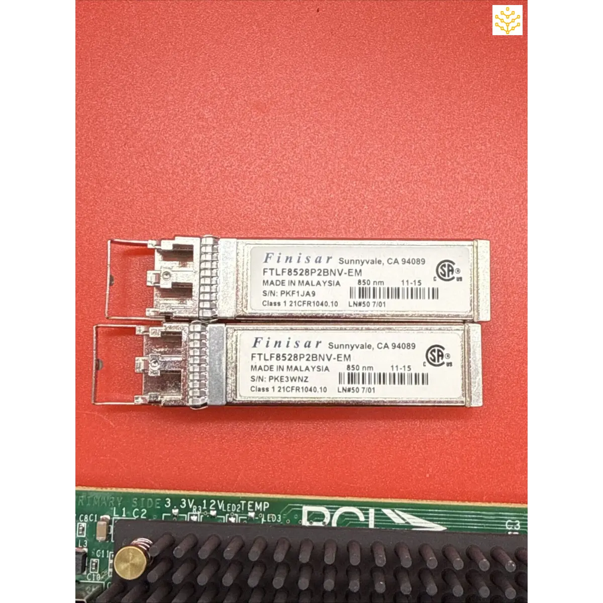 Two Finisar fiber optic SFP transceiver modules with a circuit board below them.