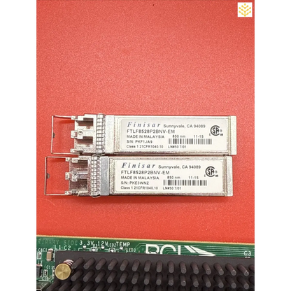 Two Finisar fiber optic SFP transceiver modules with a circuit board below them.