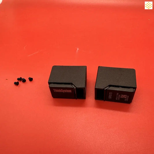 Two black ThinkSystem computer components or modules on a red surface.