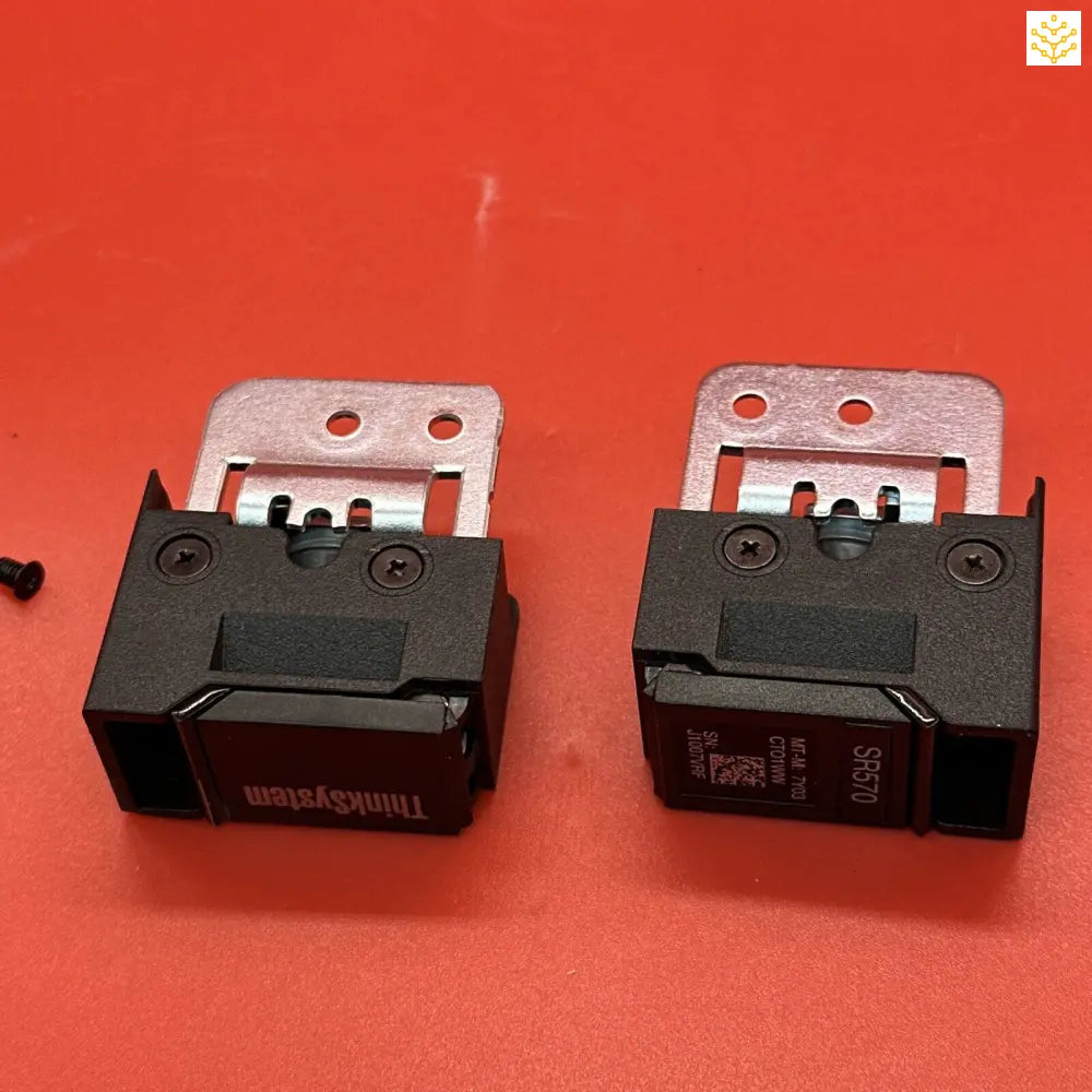 Two black electronic components or modules with metal mounting brackets attached.