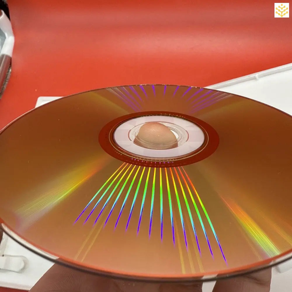 Gold-colored CD or DVD showing rainbow light reflections across its surface.