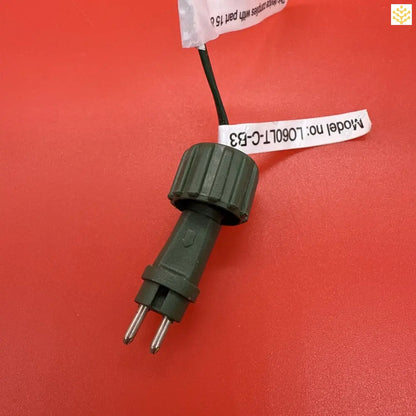 Dark green electrical power plug with a label attached.