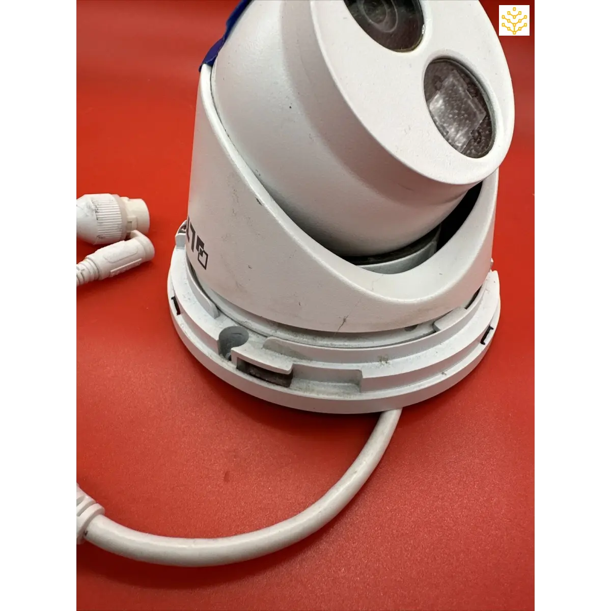 Dome-shaped security camera with two visible lens openings and a cable attached.