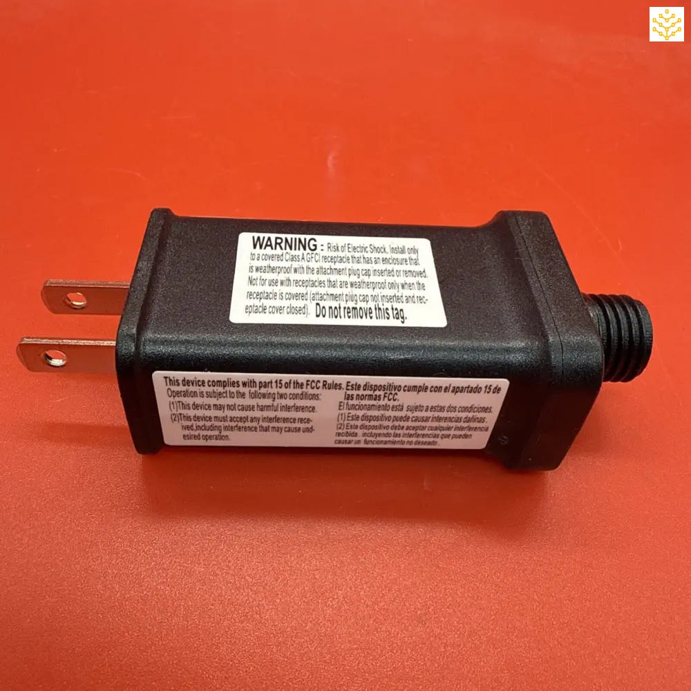 Black plastic electrical transformer with warning label and prongs.