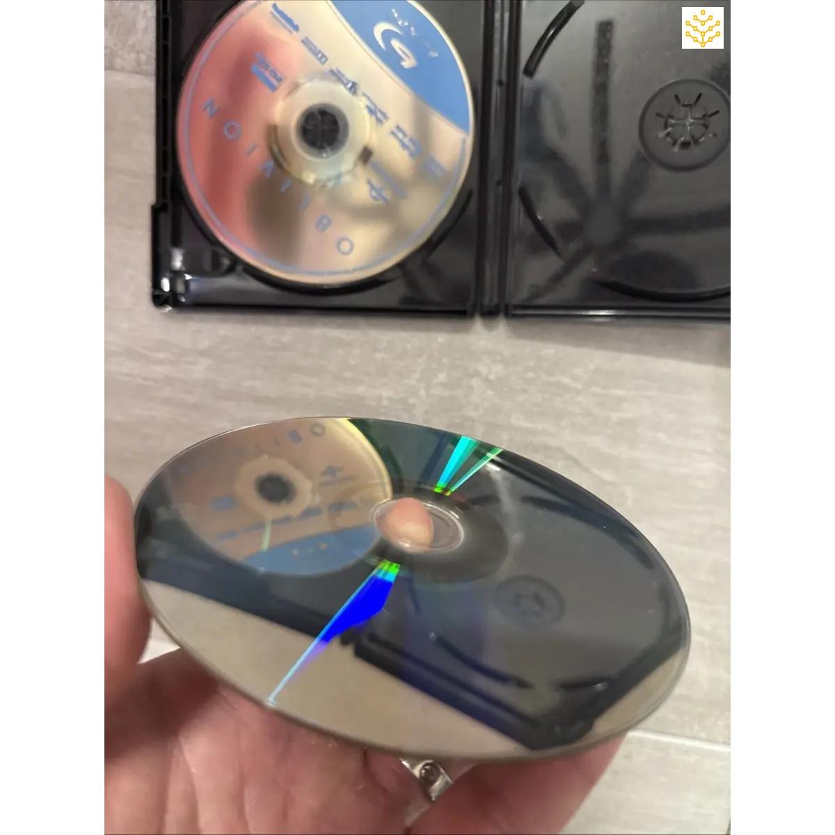 Compact disc (CD) being held and compared to another in a case.