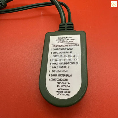 Black electronic controller with a function list printed on its surface.