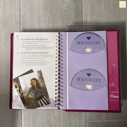 Open spiral-bound book showing ’Sex and the City’ DVD discs on one page and text with a photo on the opposite page.