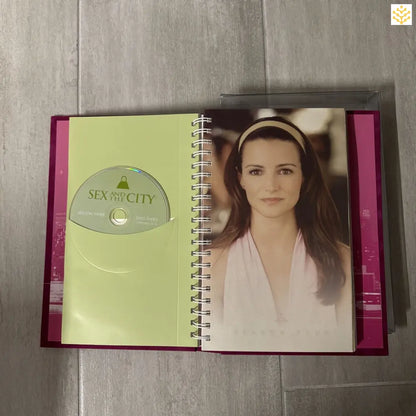 Open spiral notebook or planner with a DVD and photograph visible on its pages.