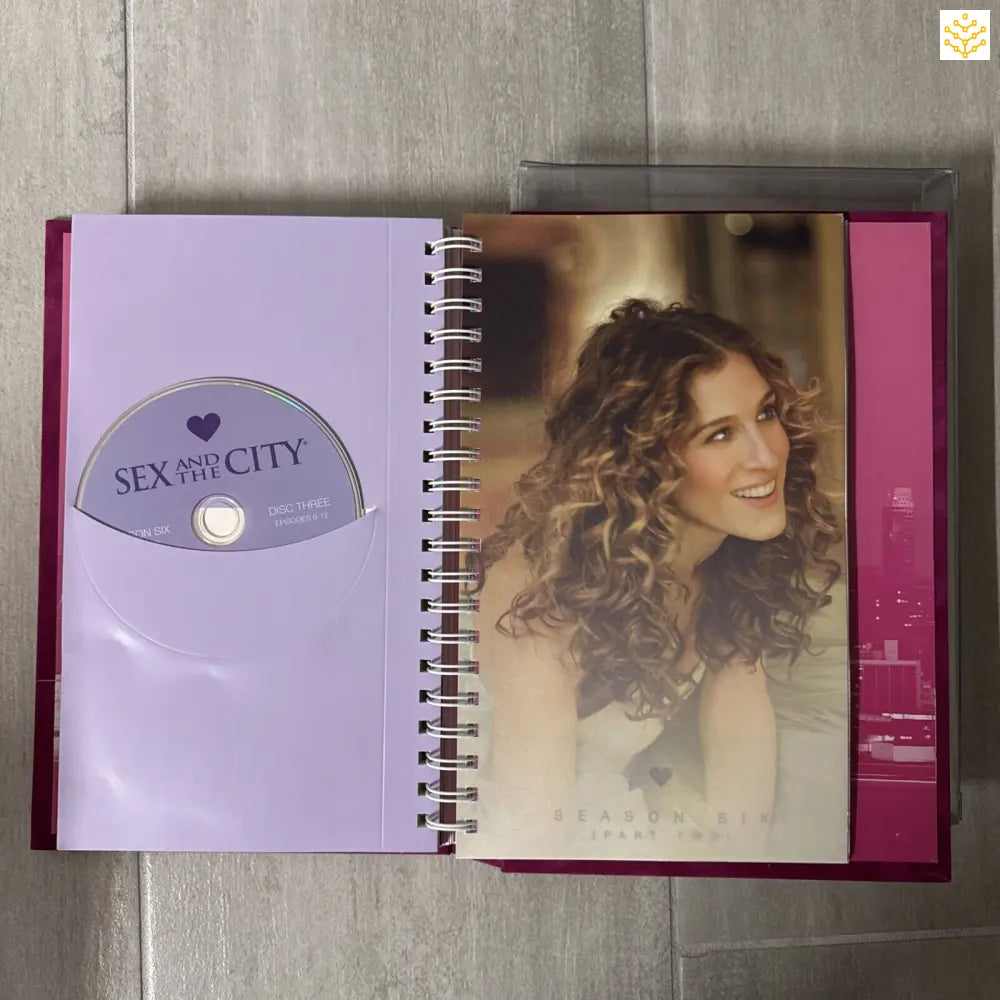 Open spiral notebook or journal featuring a Sex and the City DVD and a photo with curly hair.