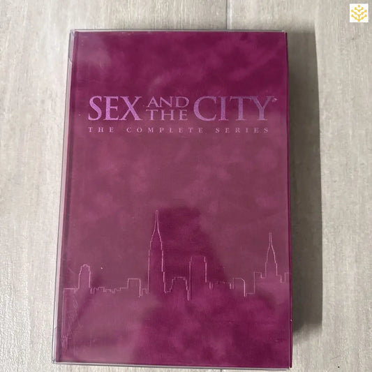 Pink DVD box set of ’Sex and the City: The Complete Series’ featuring a city skyline silhouette.