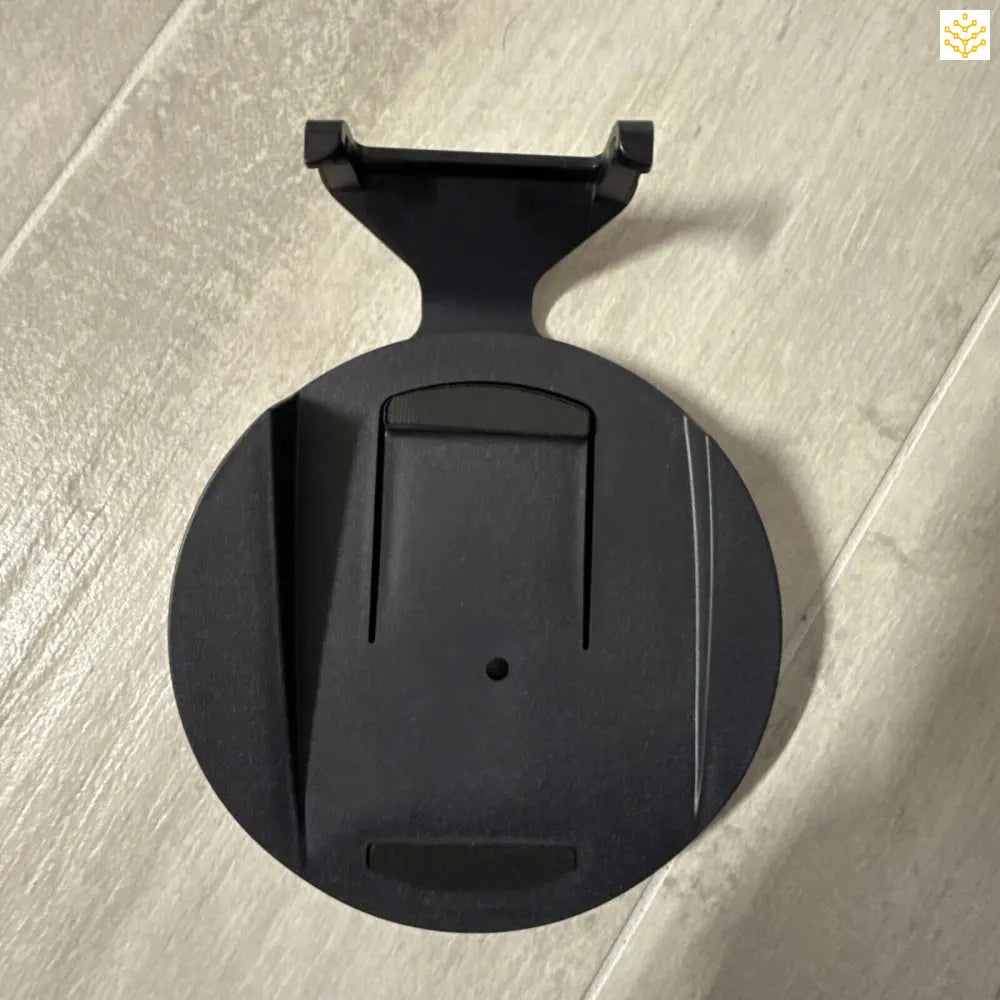 Black circular wall mount or bracket with a notched holder.