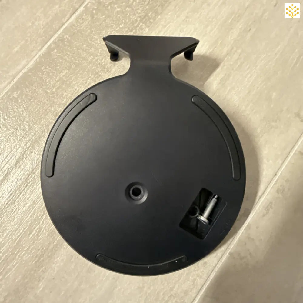 Black circular base or stand with mounting slots and a cable port.