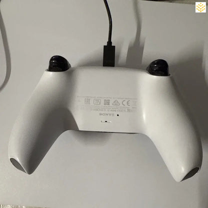 White PlayStation 5 DualSense controller with a charging cable attached.