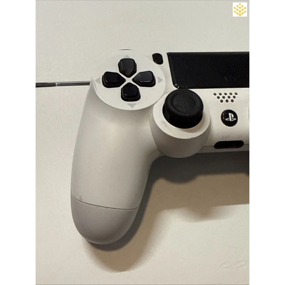 White PlayStation 4 controller with black buttons and joysticks.