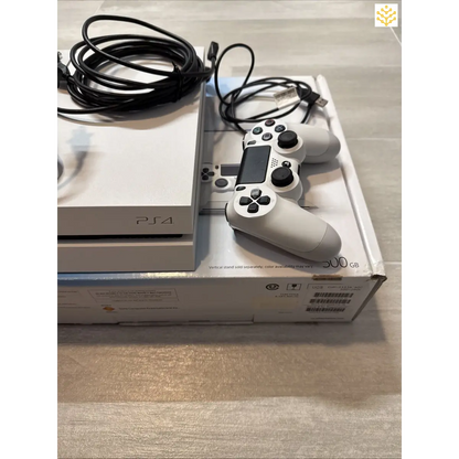 PlayStation 4 console with a white controller and cables.