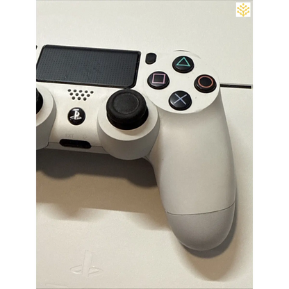 White PlayStation 4 controller with black buttons and joysticks.