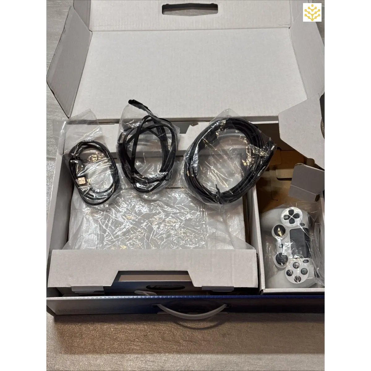 Gaming console with cables and controller in an open box.