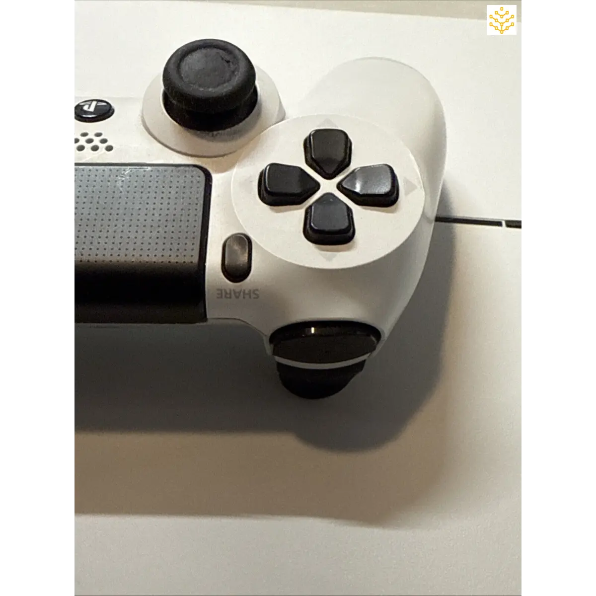 White PlayStation 4 controller with black buttons and joysticks.