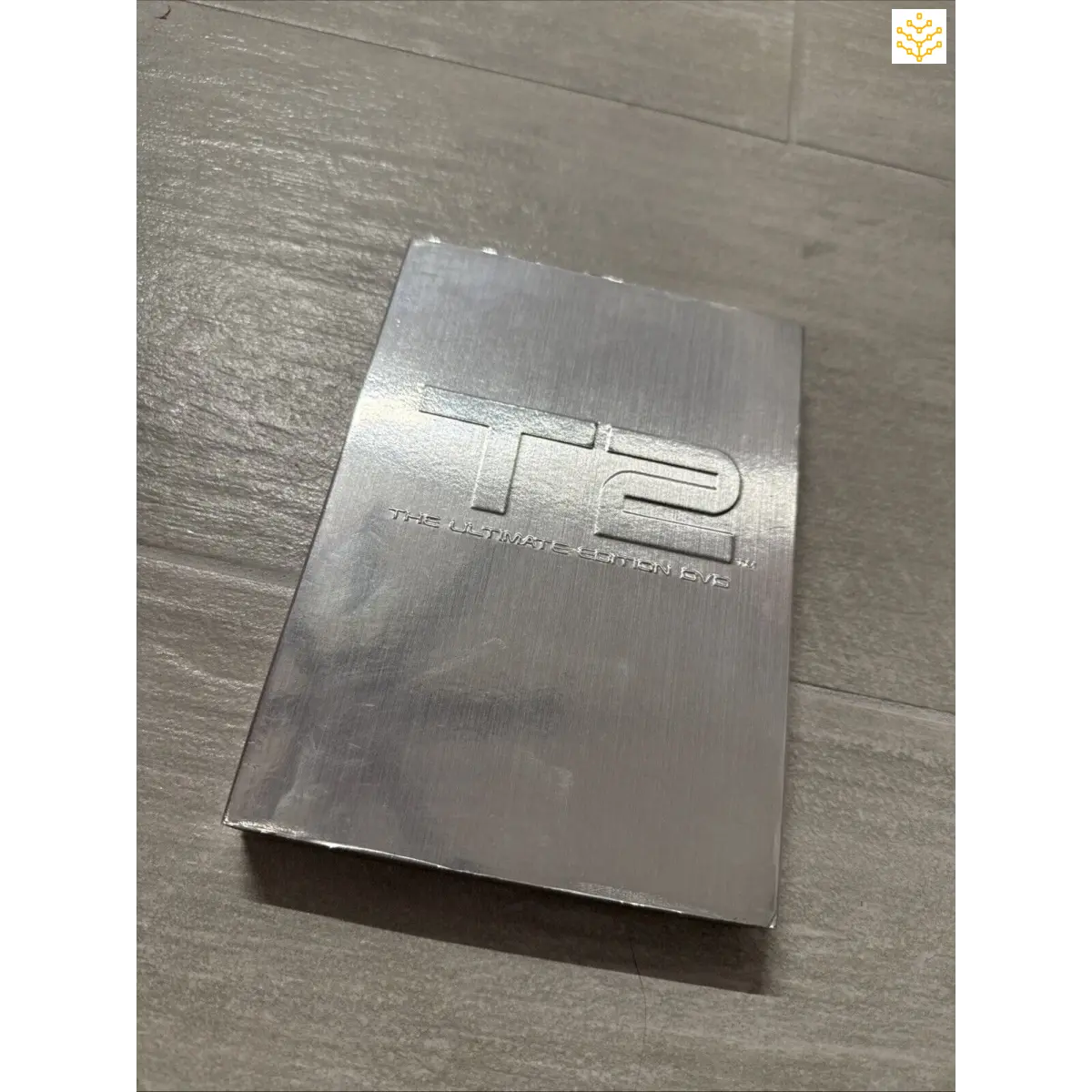 Metallic rectangular object with ’H2’’ engraved or embossed on its surface.