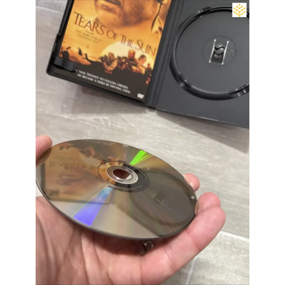 DVD disc being held with ’Tears of the Sun’ movie case visible in the background.