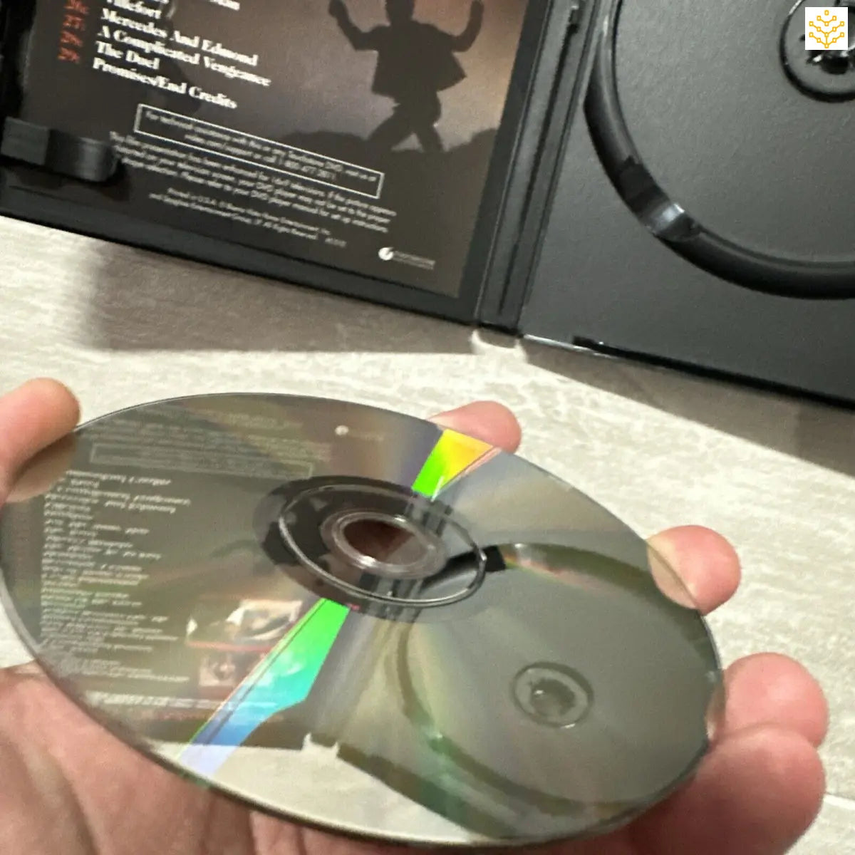 Compact disc (CD) being held by a hand, reflecting rainbow colors on its surface.