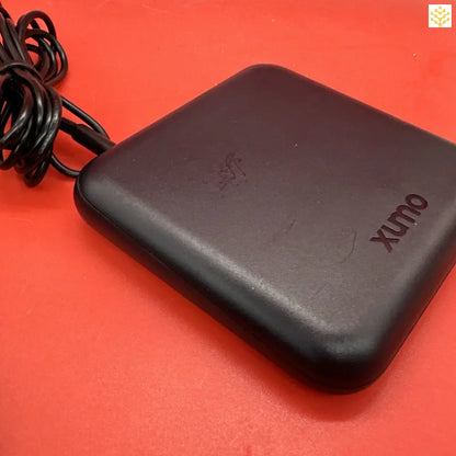 Black rectangular Xunx device with an attached cord.