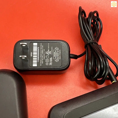 Power adapter with attached cord on a red surface.